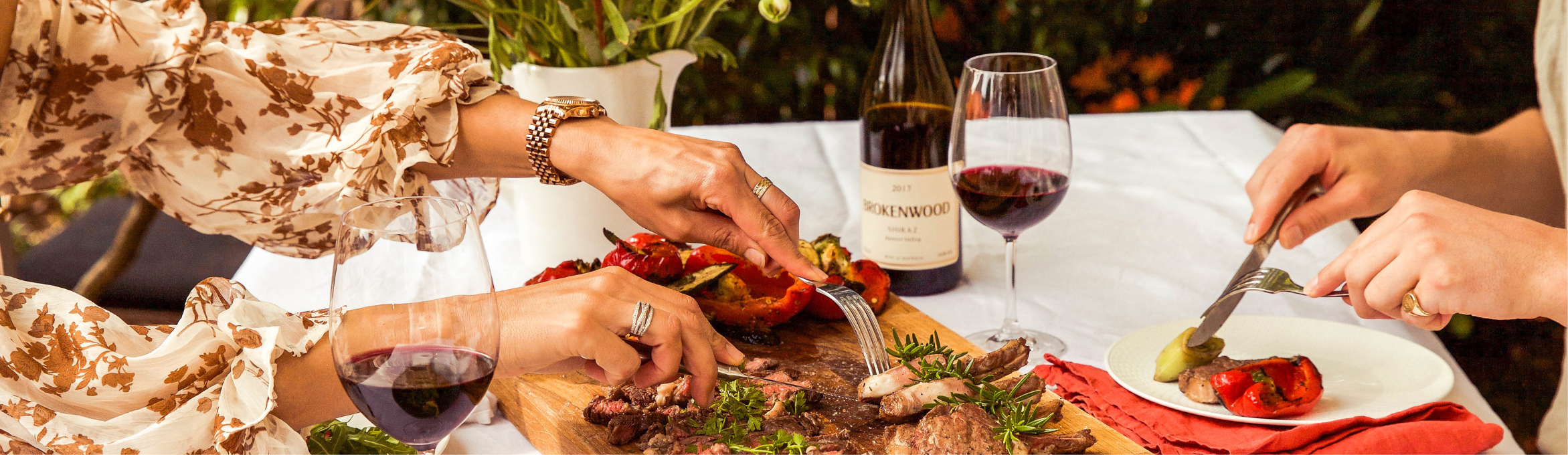 Two women having a meal with meat and red wine from Brokenwood